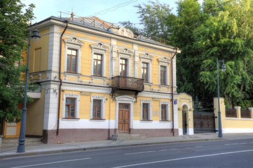 A historic building with a green roof and white walls featuring decorative window frames, located on Prechistenka street in Moscow.